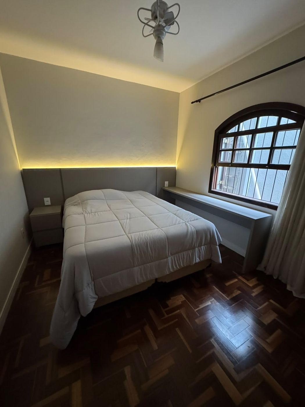 Quarto com painel de cabeceira iluminado em LED e bancada